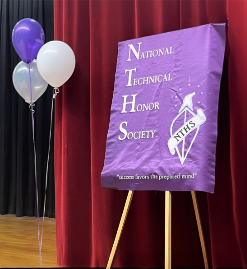 A purple NTHS sign is displayed next to a set of balloons that are purple, grey, and white.